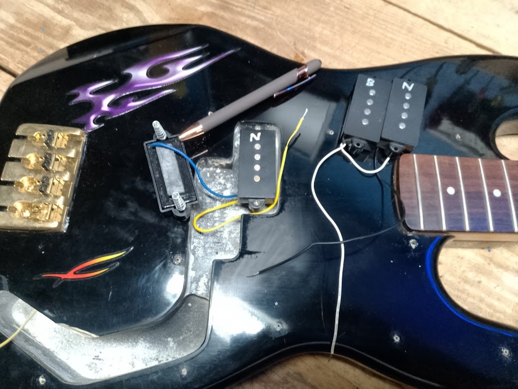 Black bass pickup cavity — three pickups loose, purple flames visible