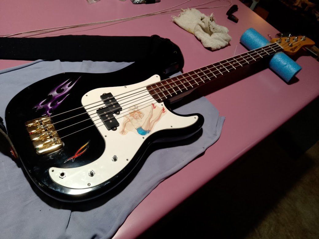 Black 5-string bass — purple flames, pin-up pickguard, gold hardware